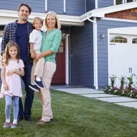 Family of four standing outside their house