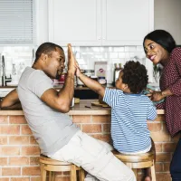 Son in between mom and dad on stool, high-fiving dad