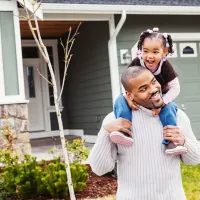 daughter on fathers shoulders outside home