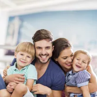 Family of four sitting close together smiling  