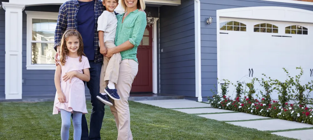 Family of four standing outside their house