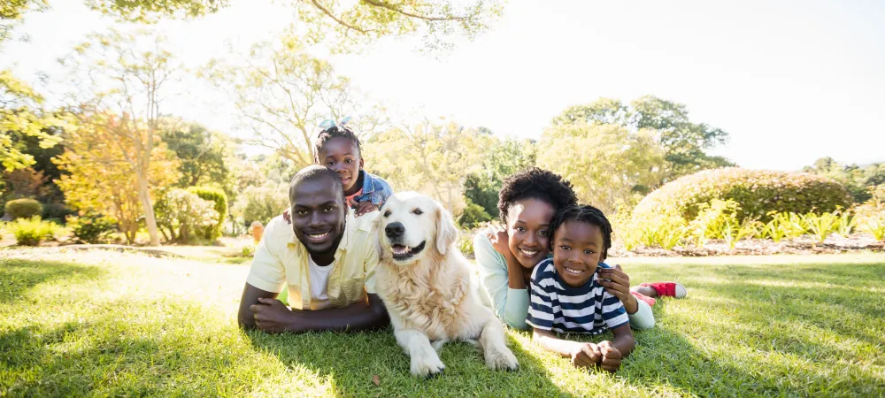Family of four and dog laying on grass outside