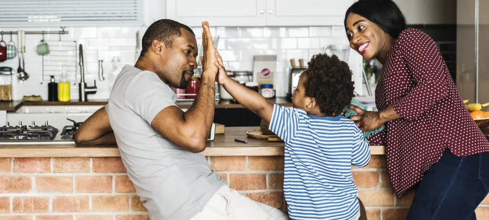 Son in between mom and dad on stool, high-fiving dad