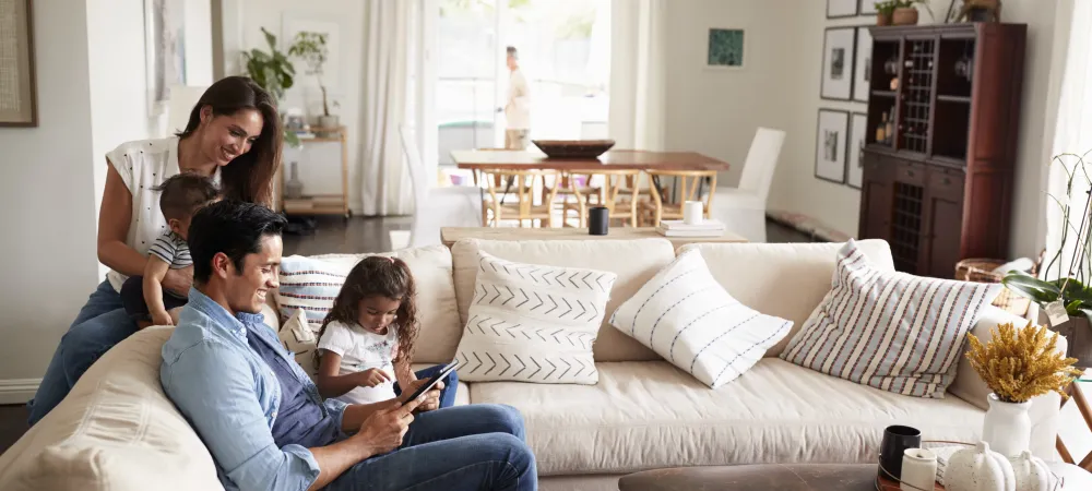 Family of four sitting on couch looking at a tablet