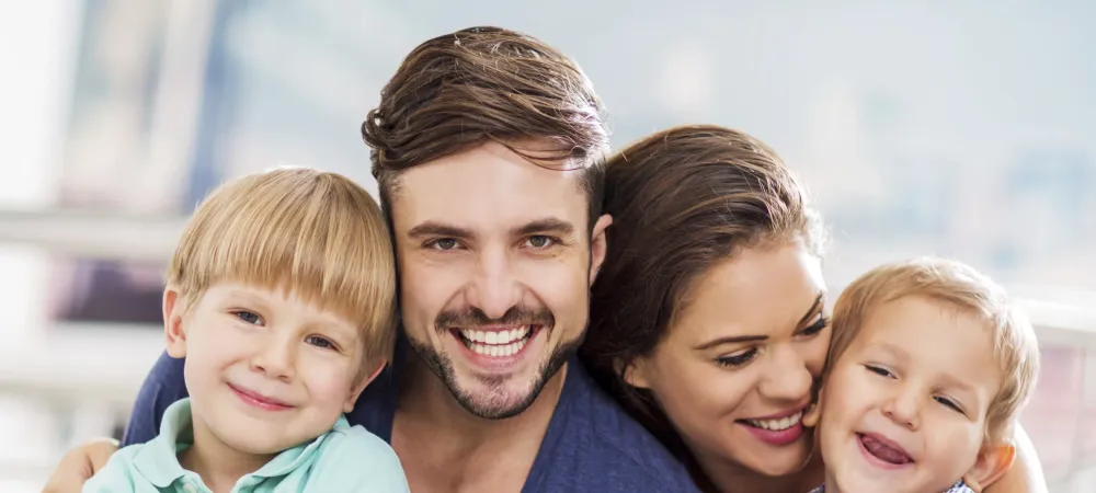 Family of four sitting close together smiling  