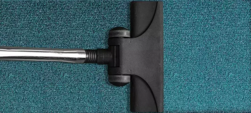 A vacuum cleaning a bluegreen carpet