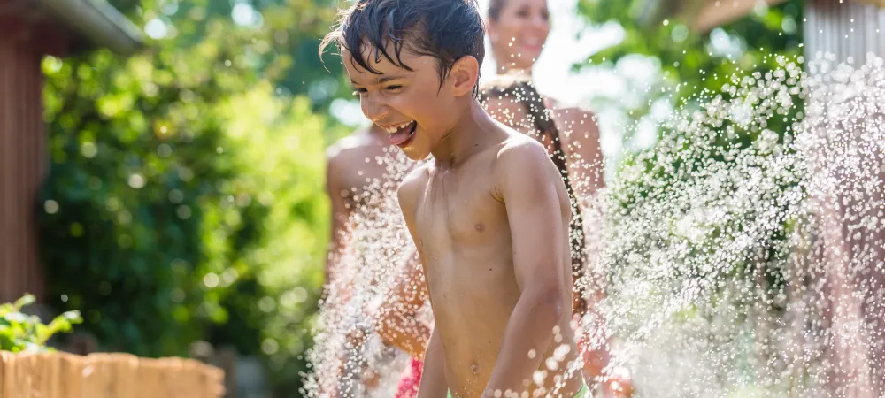 young boy running through the sprinklers
